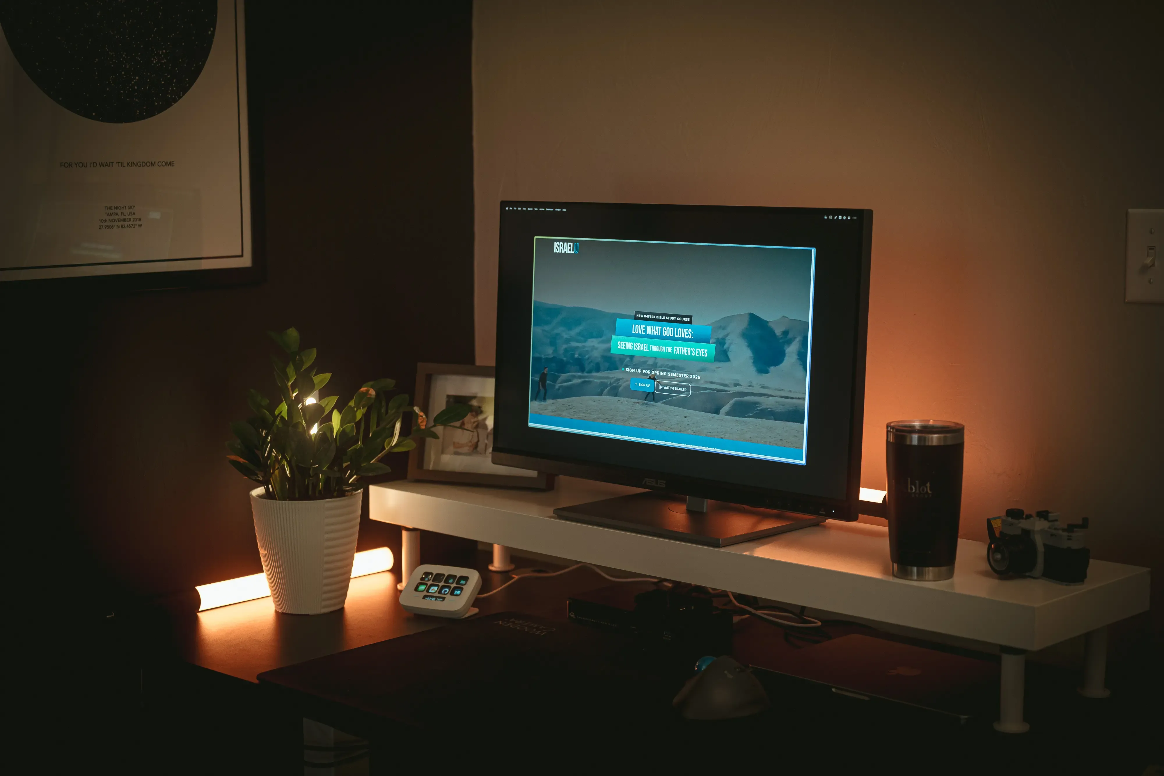 A monitor on a dimly lit desk displays israelu.org
