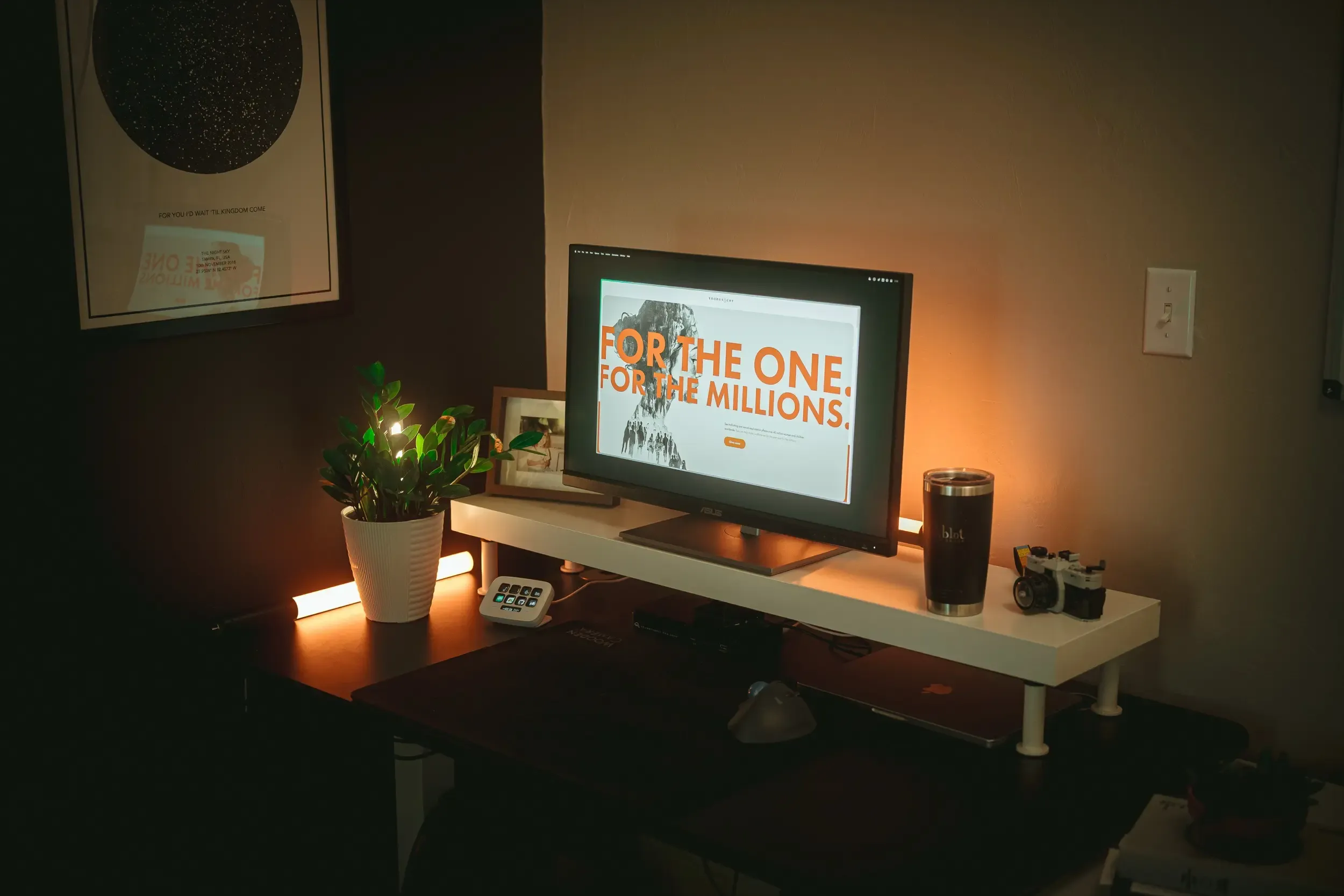 A monitor showcases the For the Millions campaign landing page on a dimly lit desk.