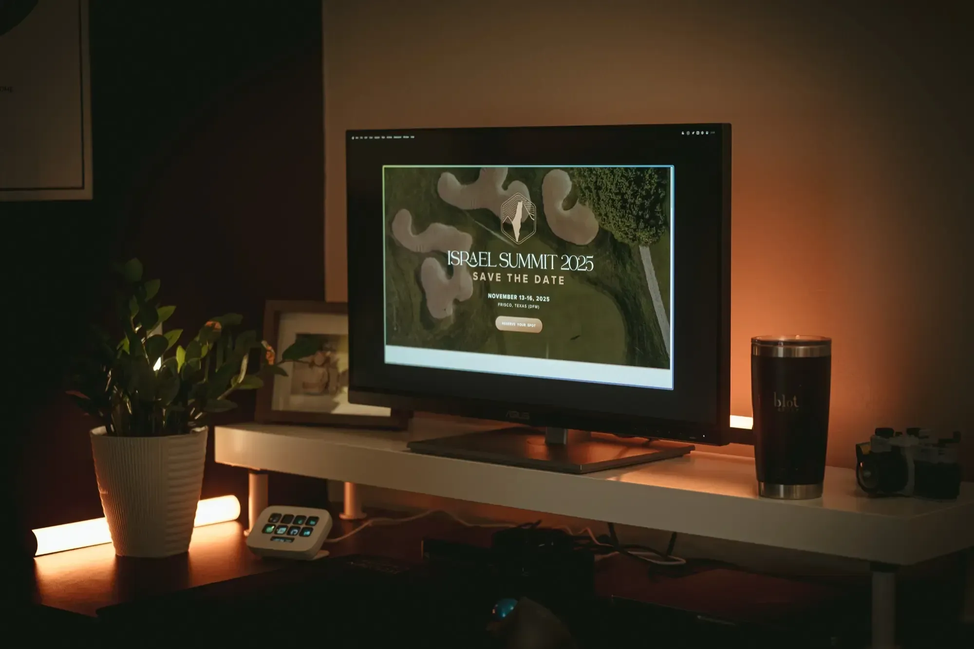 A desk, with a computer monitor showing a website for the Israel Summit event