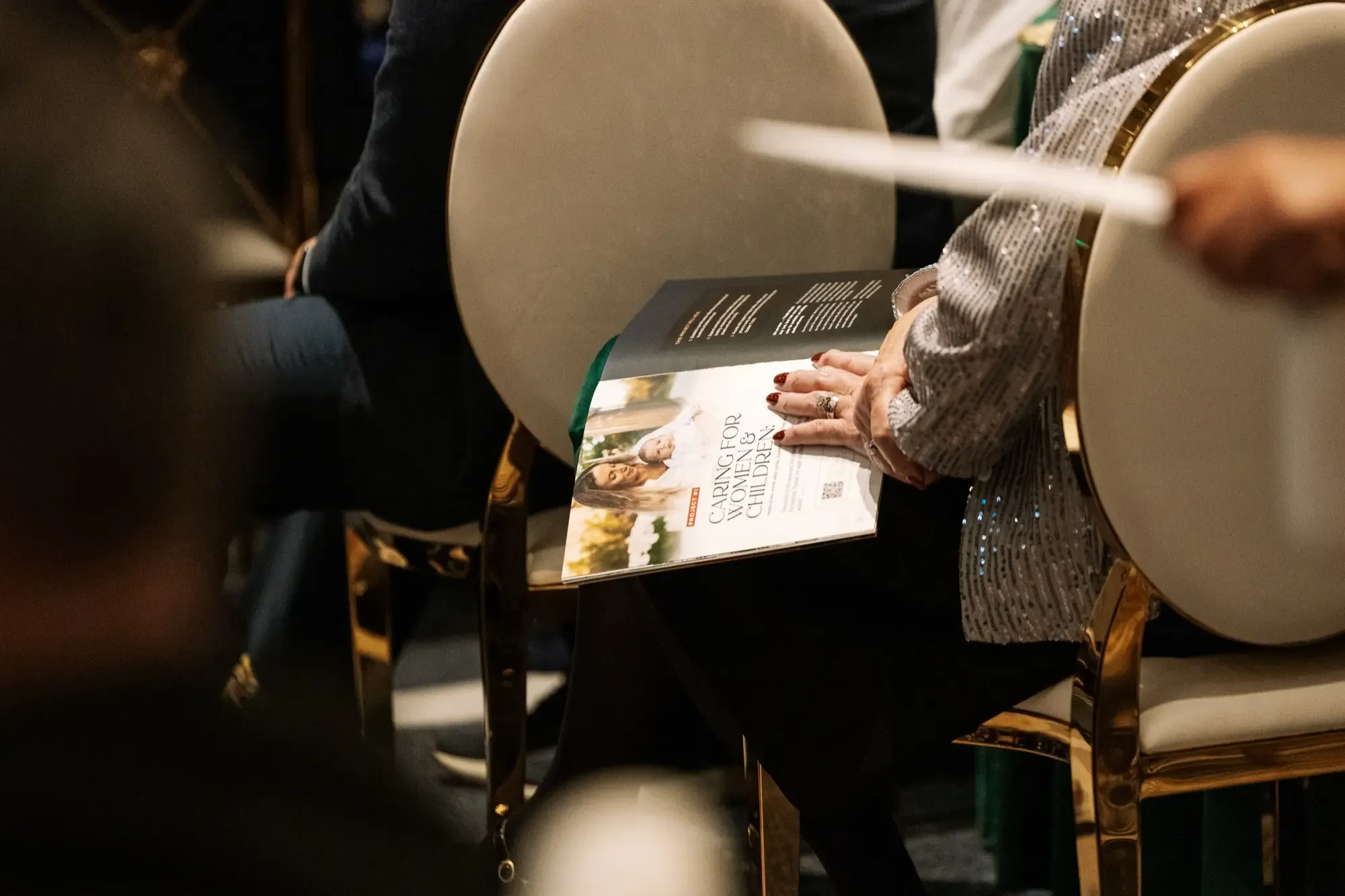 A woman sits at the Gala with an open fundraising booklet