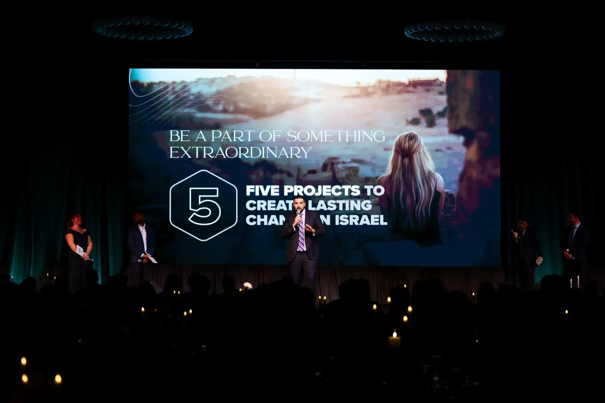 A huge LED screen shows the words "5 projects to create lasting change in Israel"